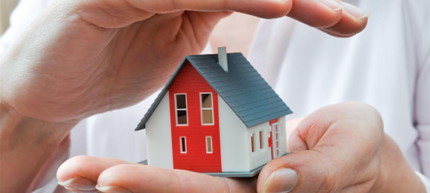 A little wooden house - red, white and blue - being cradled between a pair of hands