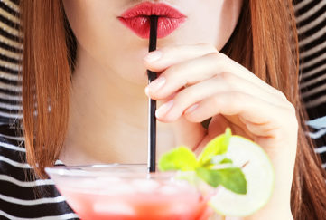 young woman in sunhat drinks cocktail