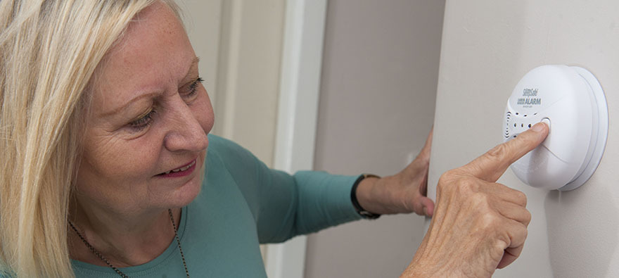 Woman checking smoke alarm