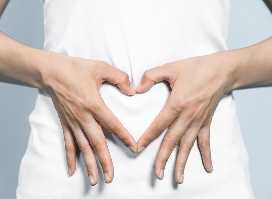 woman making heart shape with hands over her tummy