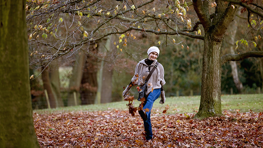 Woman kicking leaves in autumn time