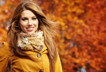 Woman dressed in mustard in park with autumn leaves on tree