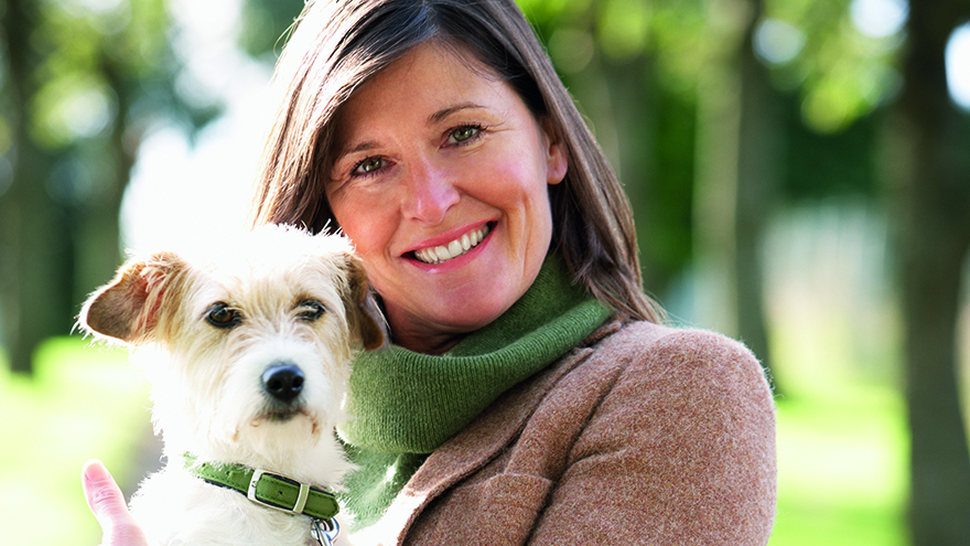 Woman Walking Dog Outdoors In Autumn Park