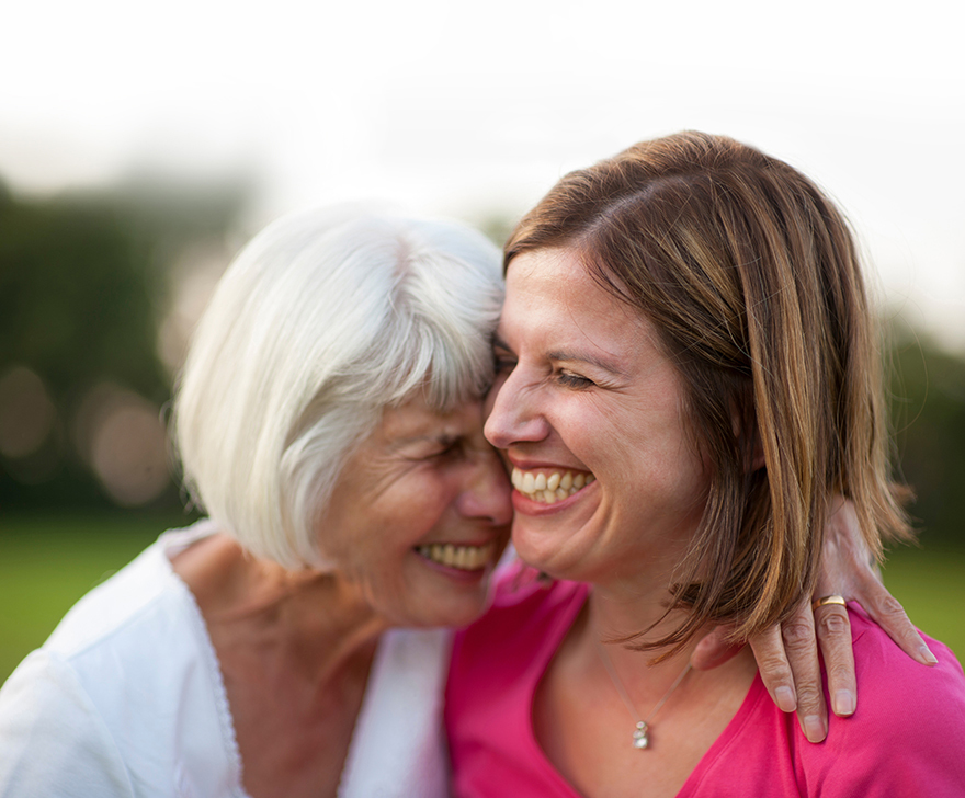 senior mother and mature daughter laughing and hugging