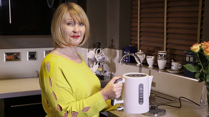 Woman making cup of tea with white kettle