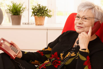 Woman using landline phone sitting in armchair in living room Pic: Istockphoto