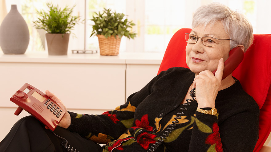 Woman using landline phone sitting in armchair in living room Pic: Istockphoto