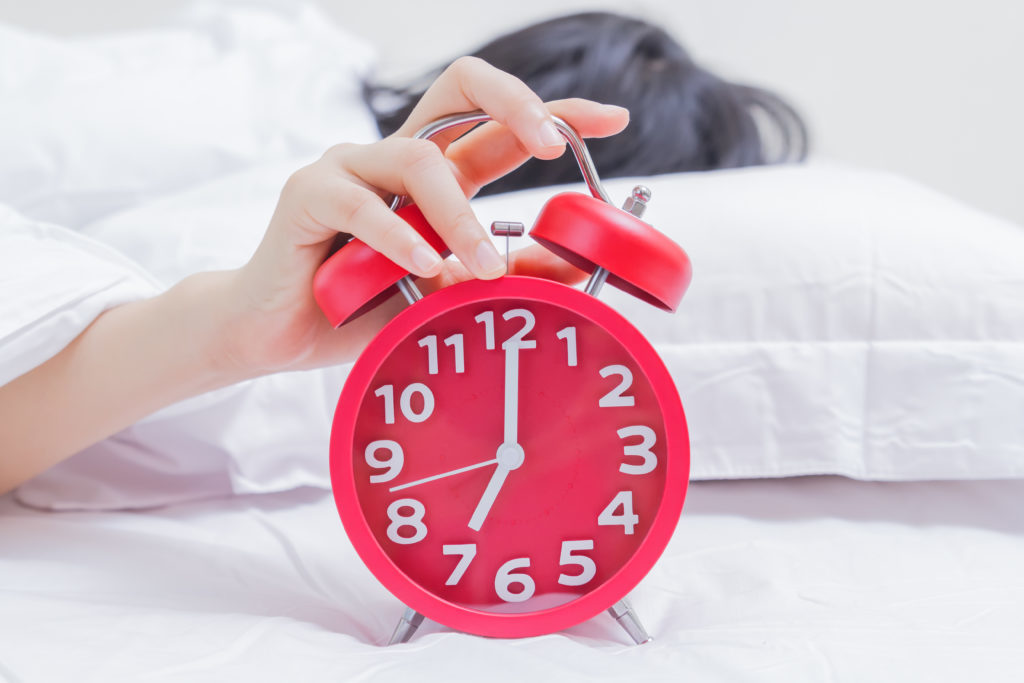 Hand hitting red alarm clock