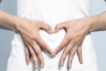 Hands in shape of heart over woman's tummy
