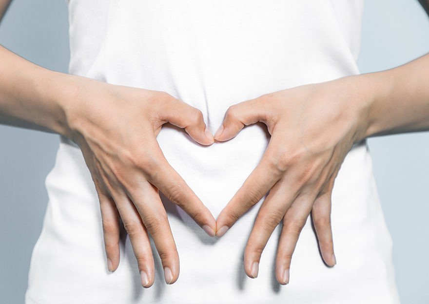 Hands in shape of heart over woman's tummy
