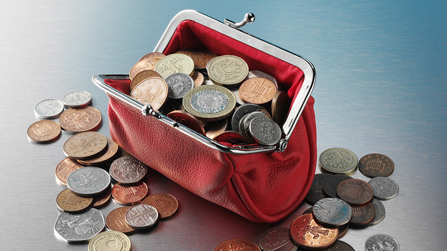 Purse full of British money on a stainless steel background.