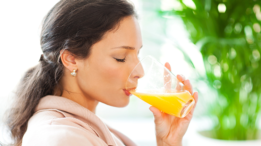 Beautiful woman drinking freshly squeezed orange juice.