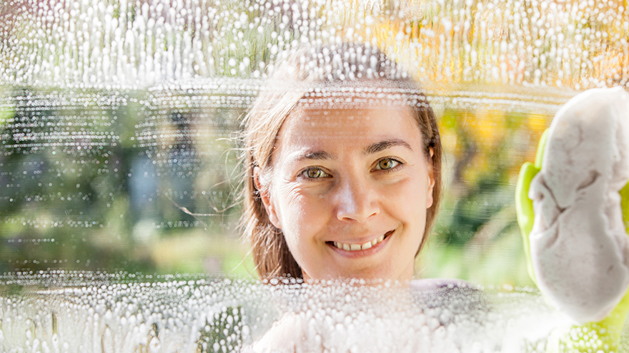 Young woman cleaning windows on a clear sunny day.