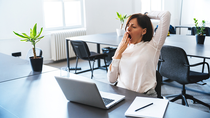 Young businesswoman yawning in front of laptop