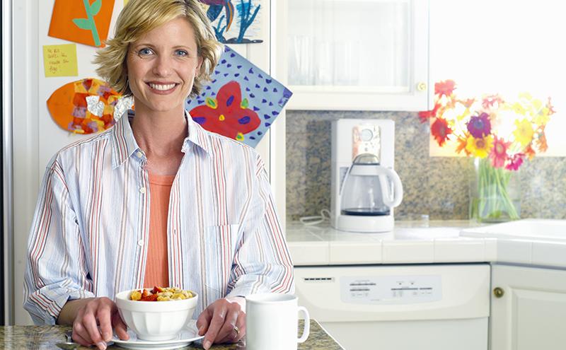 Woman eating breakfast alone in kitchen, peaceful