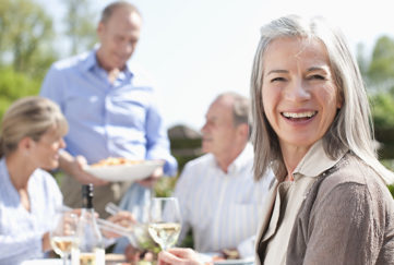 Portrait of smiling woman drinking wine at patio table with friends