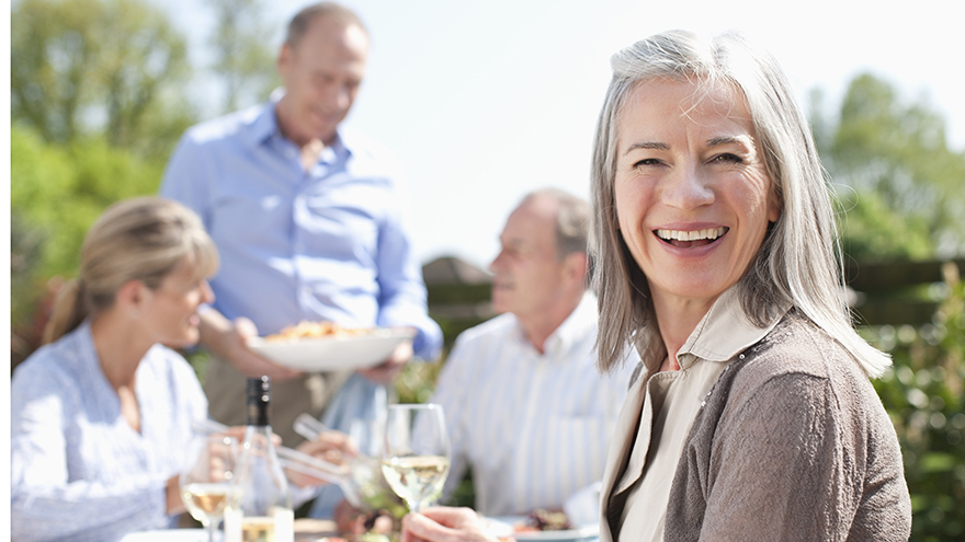 Portrait of smiling woman drinking wine at patio table with friends