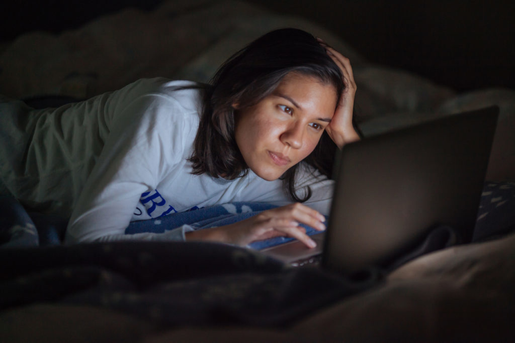 Woman watching laptop in her bed