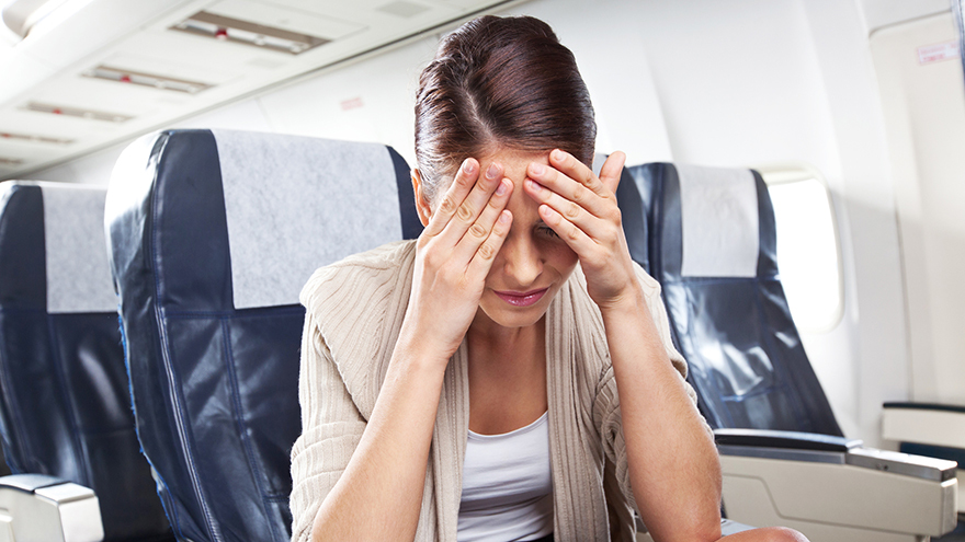 A young woman sitting on an airplane and suffering from headache.
