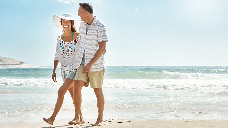 Shot of a mature couple walking along the beach