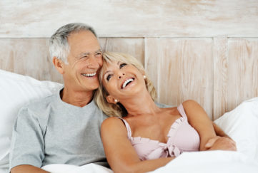 Portrait of a joyful mature couple smiling together in bed