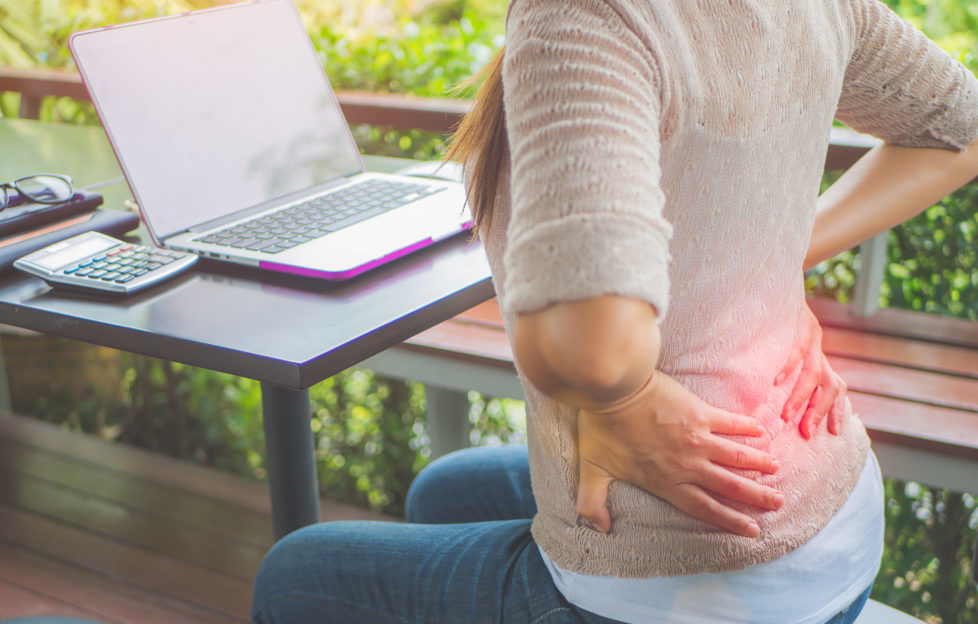 Closeup woman with hands holding her waist back in pain. Office syndrome and Health-care Concept.