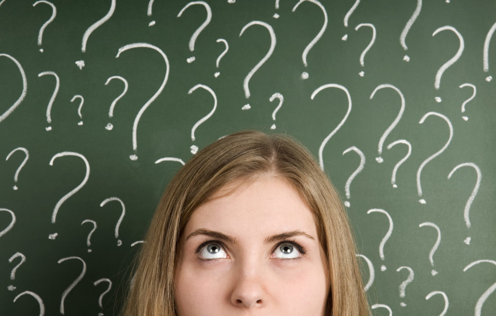 thinking woman in front of question marks written blackboard