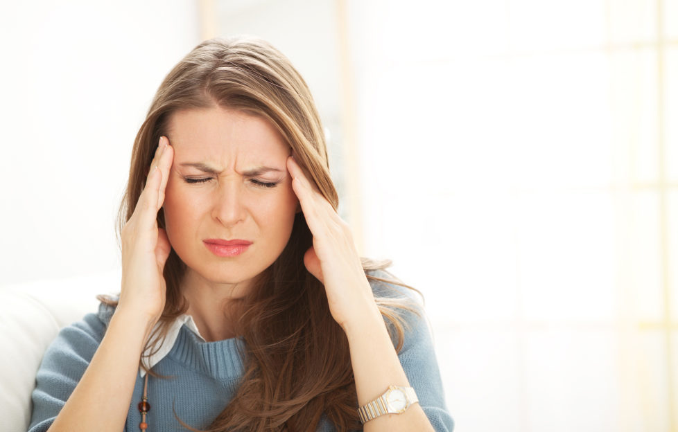 Woman having head ache holding hands on temples.