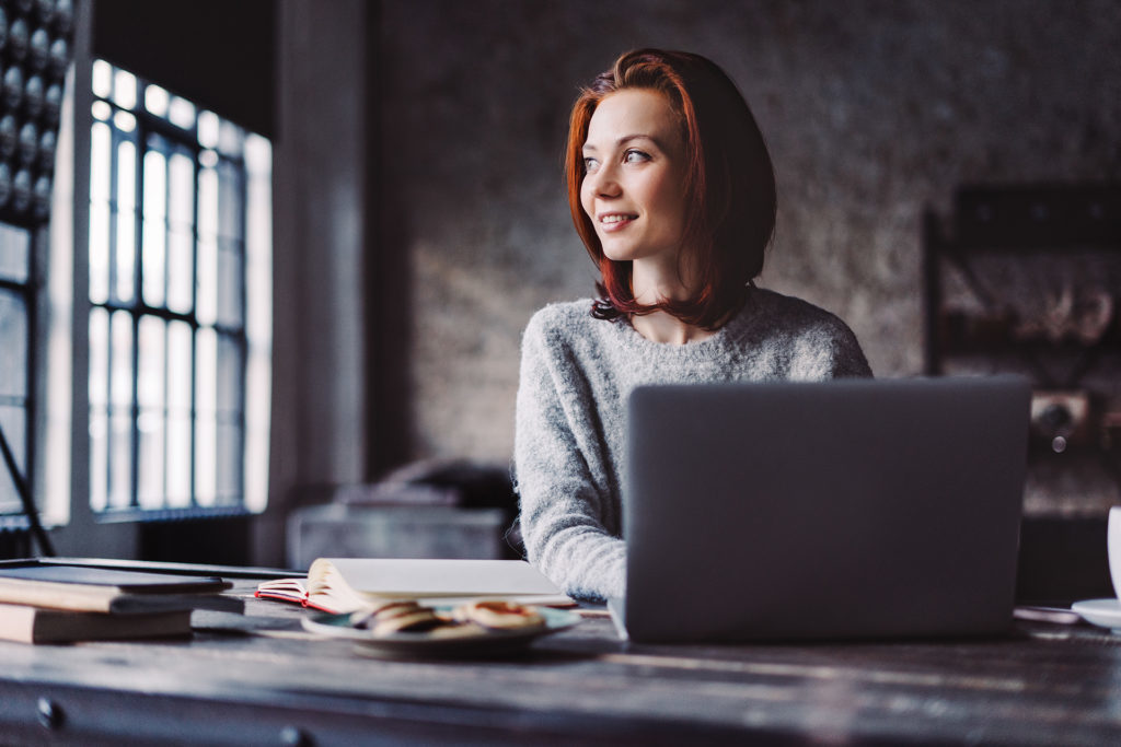 Young woman using laptop in a loft apartment