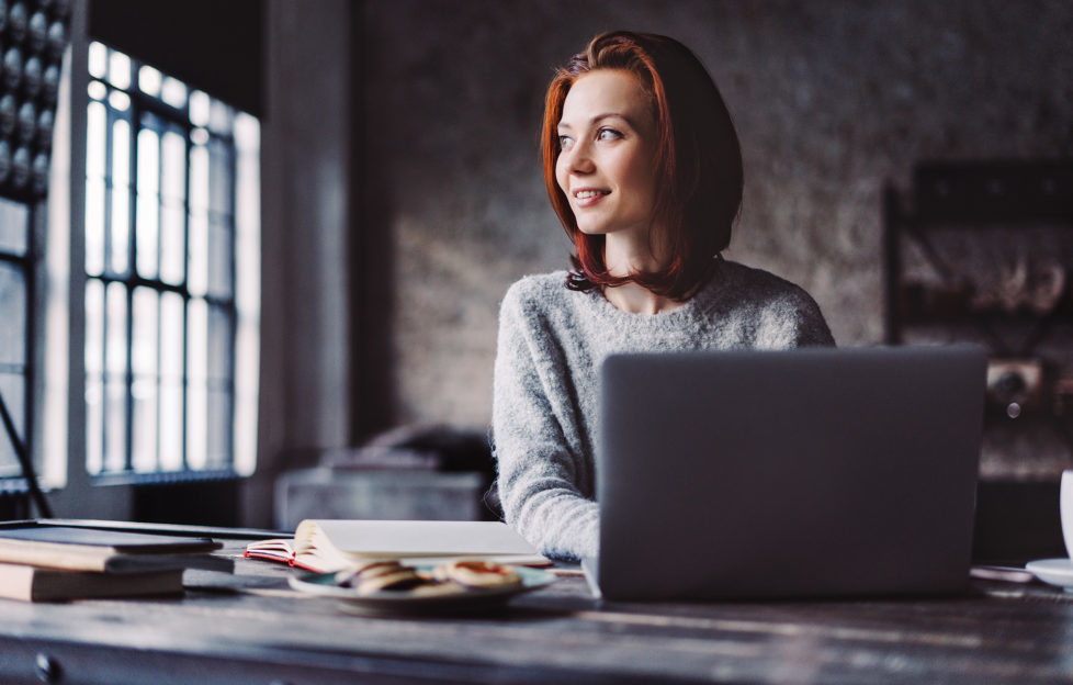 Young woman using laptop in a loft apartment