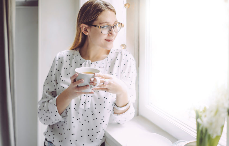 2 women with cups of tea chatting on white sofa