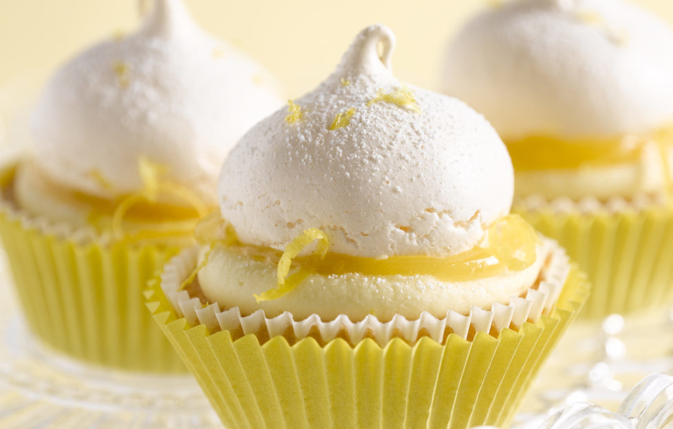 Three lemon meringue cupcakes in yellow cake cases