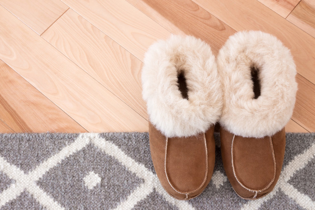 Gray rug and warm slippers on wooden floor.