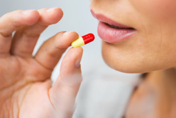 close up of woman taking medicine in pill