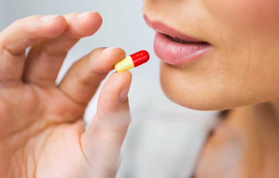 close up of woman taking medicine in pill