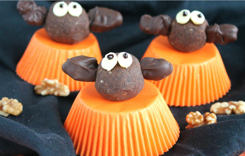 Bat shaped energy bites sitting on orange upturned cupcakes