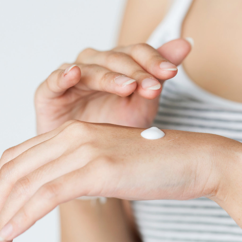 Woman applying cream to the back of her hand