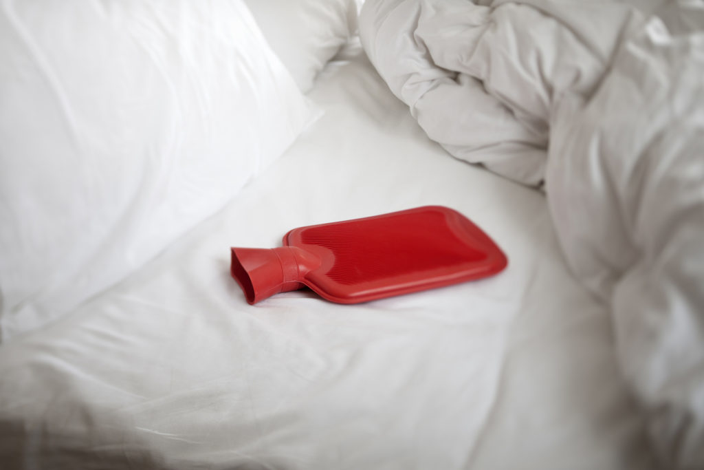 Red hot water bottle on bed