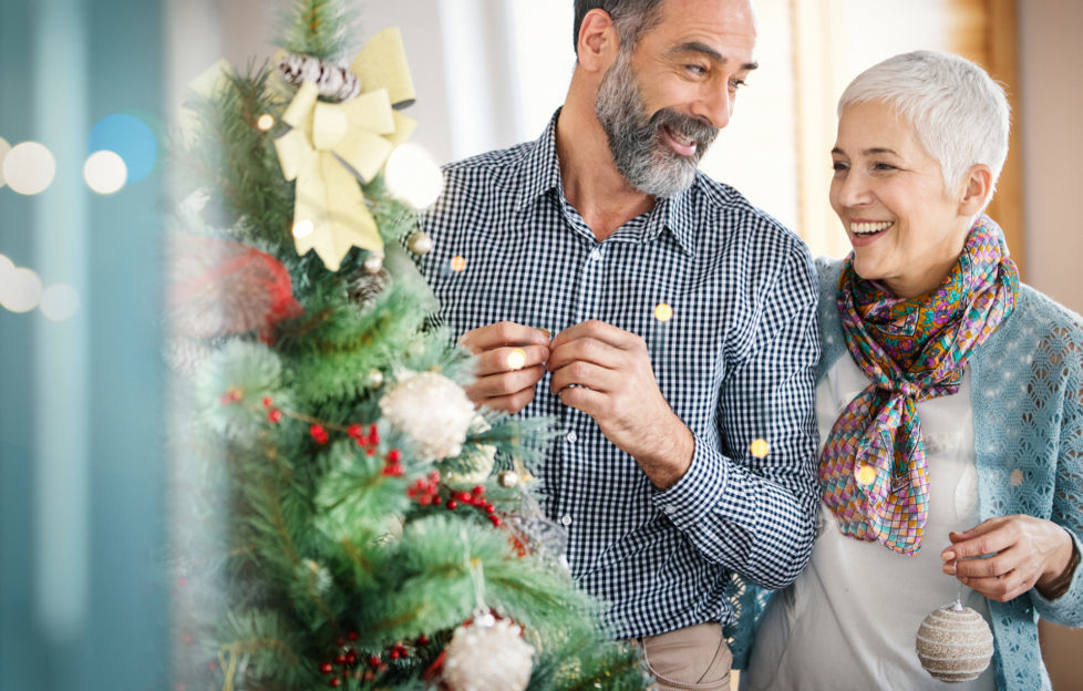 Senior couple decorating a Christmas tree.