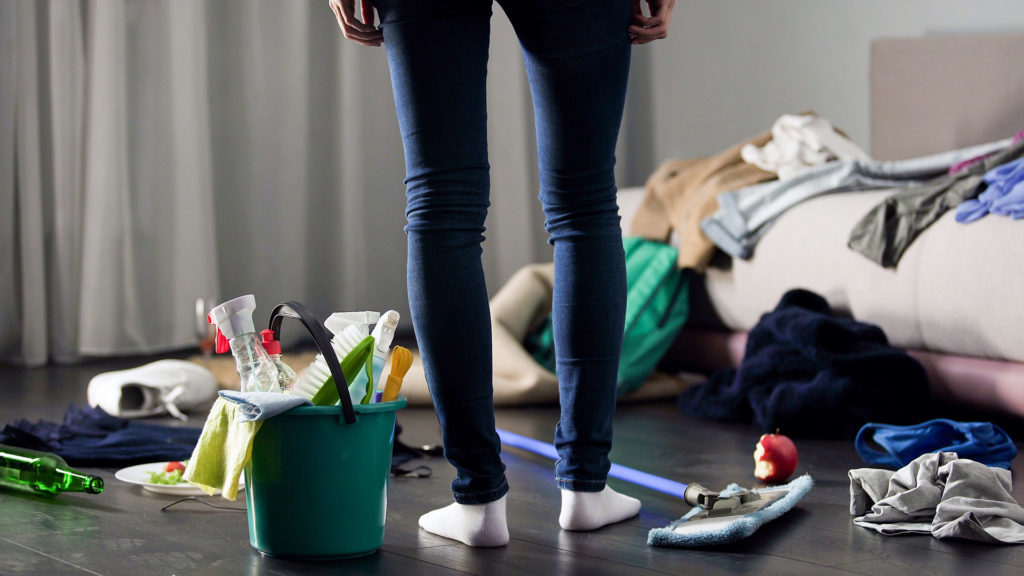 Woman looking at mess in flat and about to clean