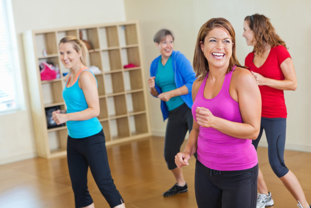 Happy women working out together in fitness exercise class.