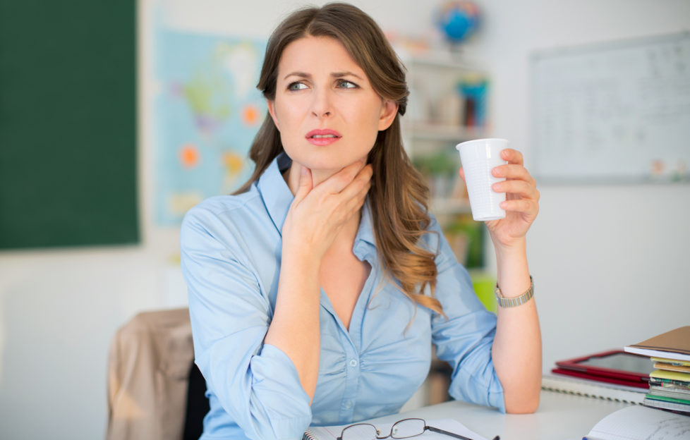 Woman with sore throat at desk