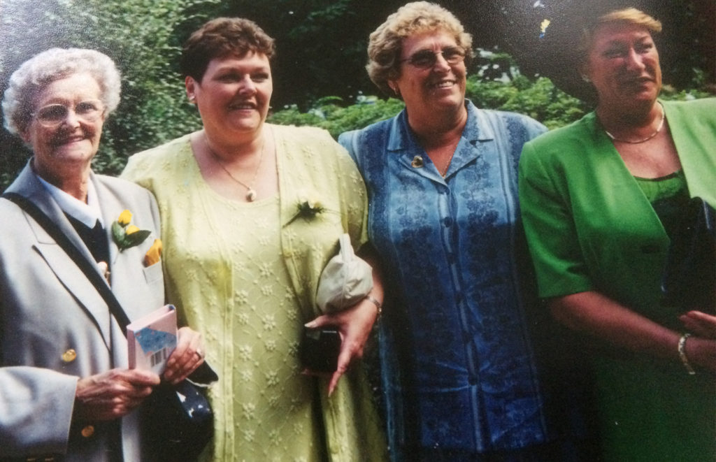 Smiling elderly lady with three mature ladies, her daughters, at a wedding