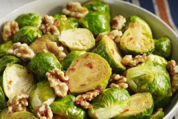 A bowl of Brussels sprouts, sliced in half, dressed with honey, chilli and walnuts