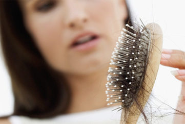 Woman looking at hair clogging up hairbrush