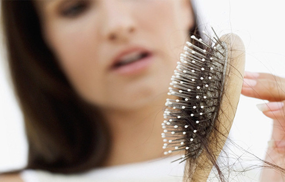 Woman looking at hair clogging up hairbrush