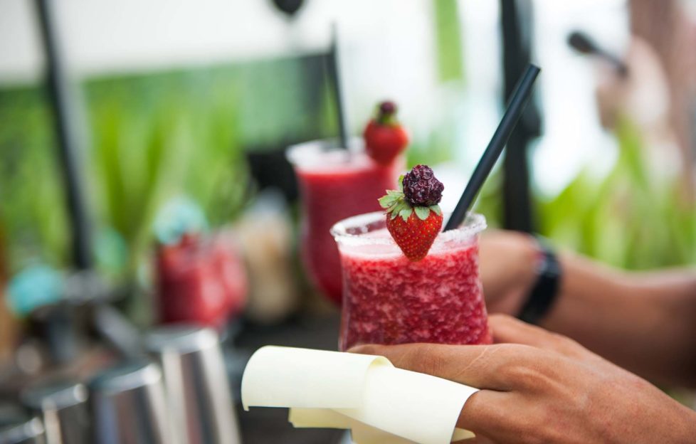 Waiter holding strawberry cocktail, focus on the strawberry