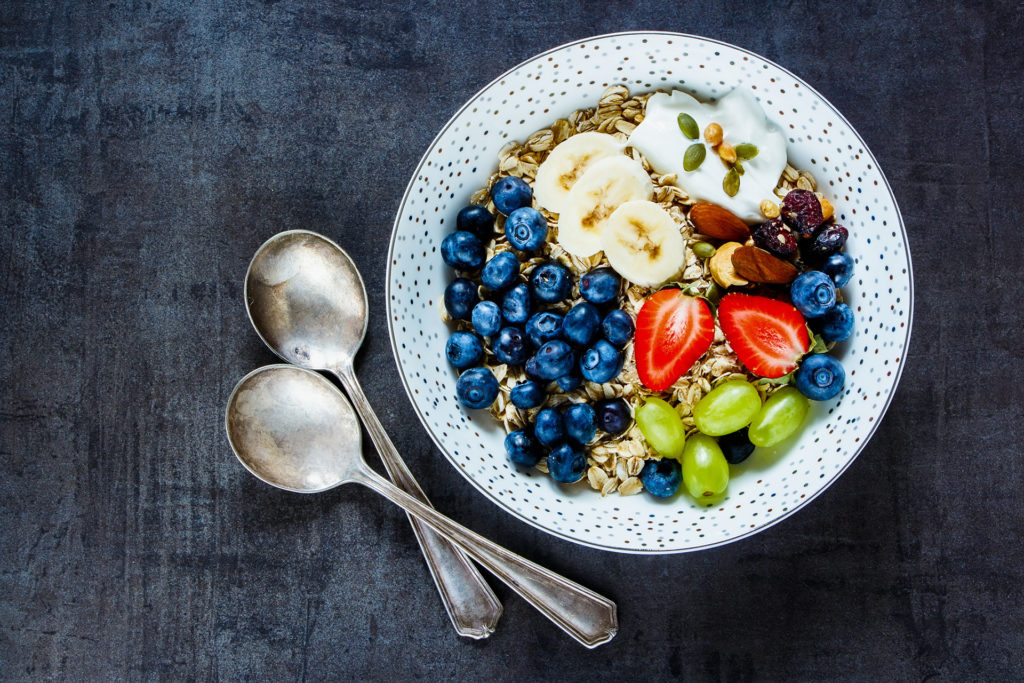 Plate of oat flakes, berries with yogurt and seeds for tasty breakfast on dark vintage background - Healthy food, Diet, Detox, Clean Eating or Vegetarian concept.