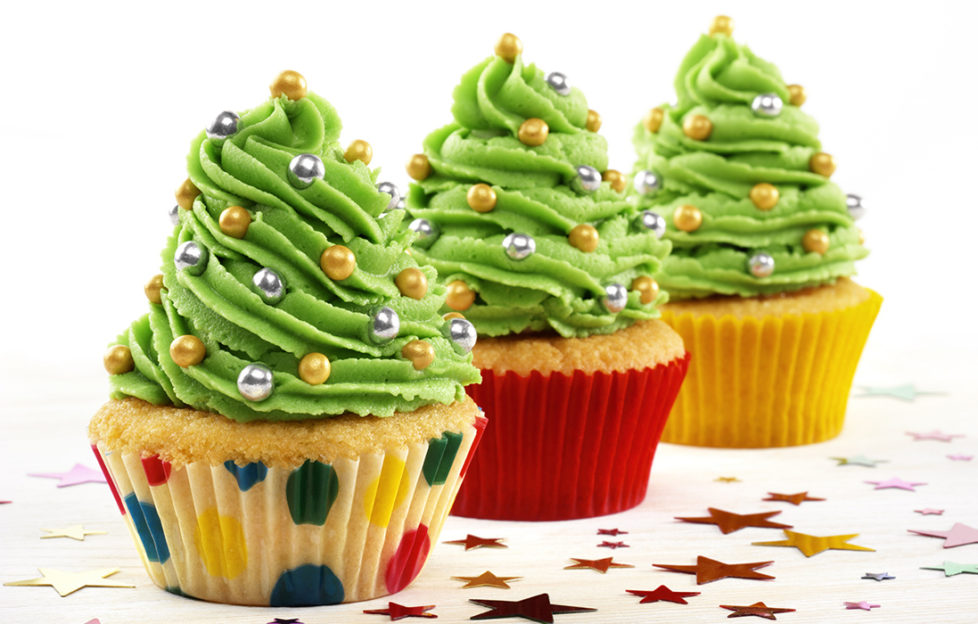 Three cupcakes with a tall swirl of green icing resembling Christmas trees, with sprinkles