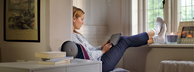 Lady with tablet sitting on window seat at home